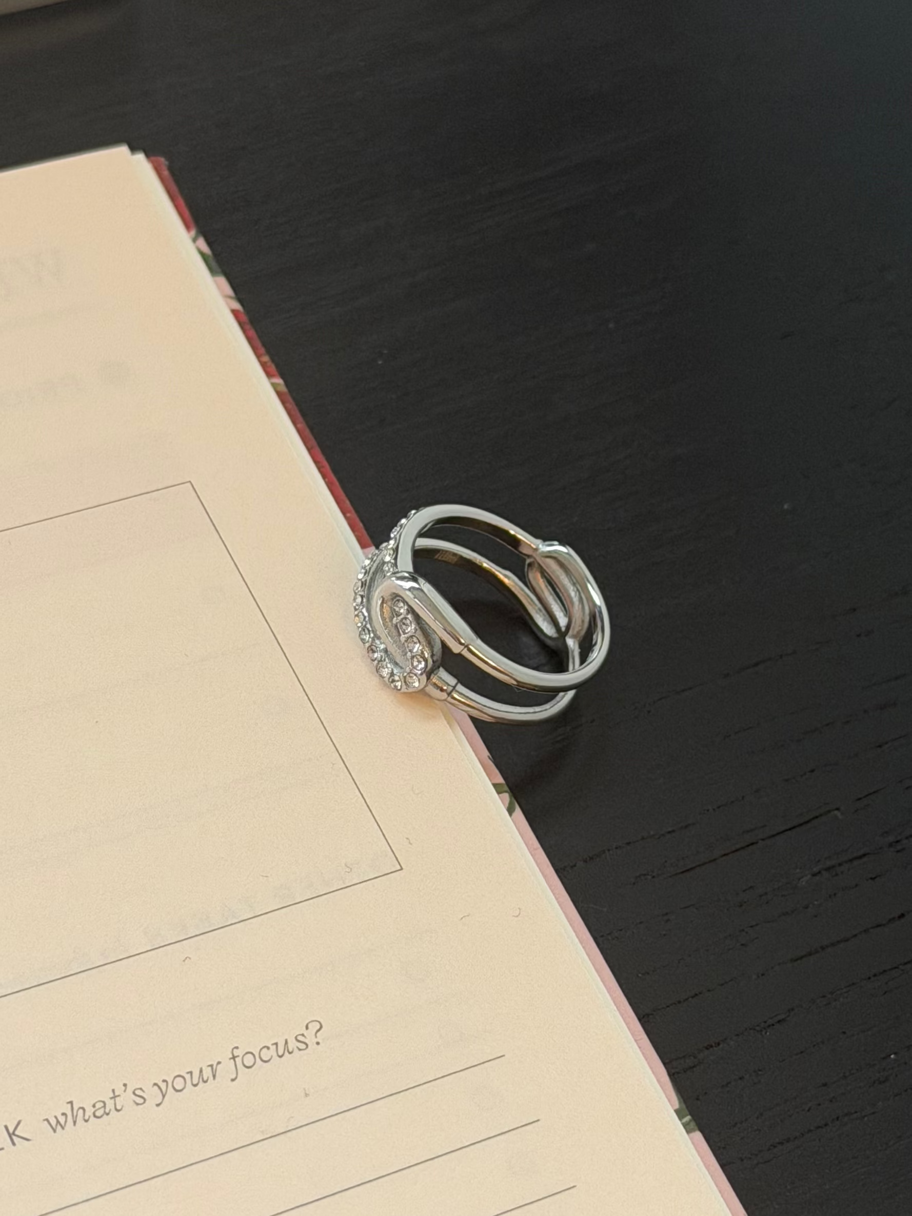 Stack of silver rings on a notebook with text on a dark surface