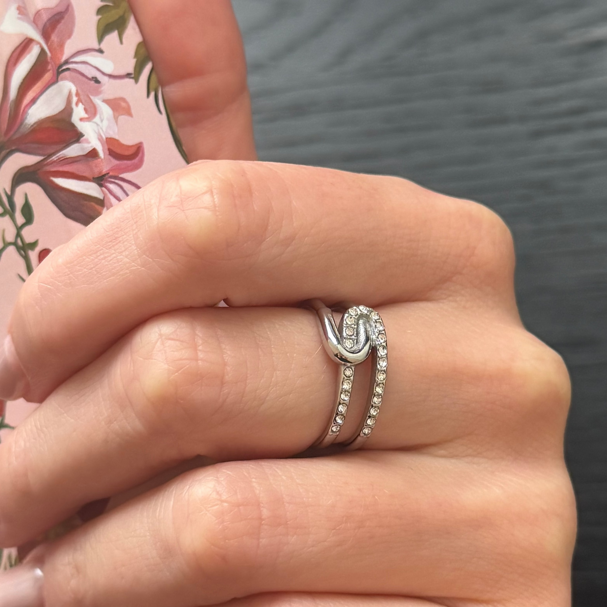 Close-up of a hand wearing a silver ring with a blurred background