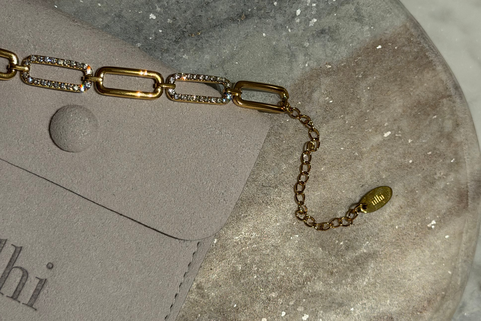 Gold chain bracelet with diamond accents on a gray surface