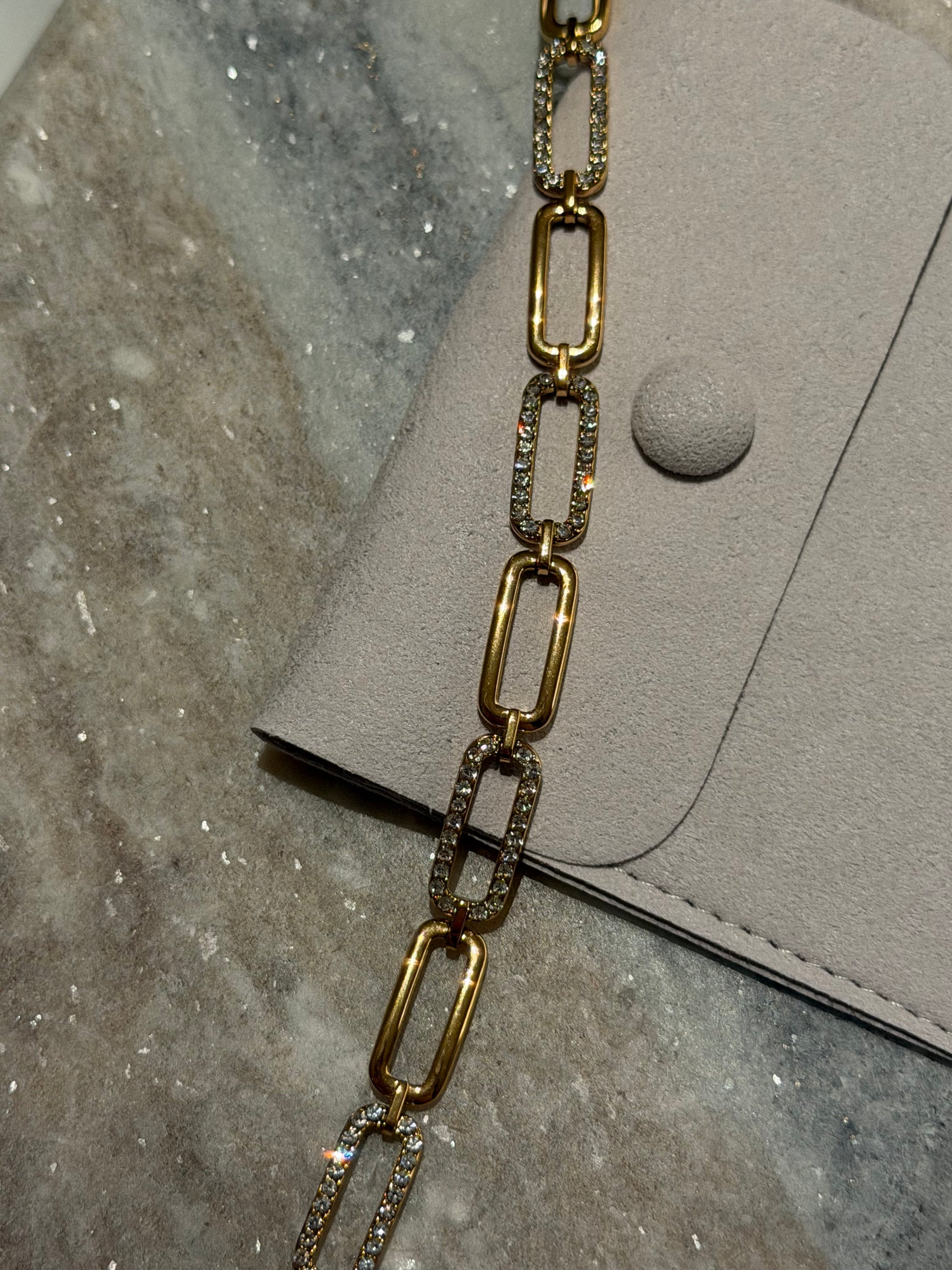 Gold chain bracelet on a textured surface