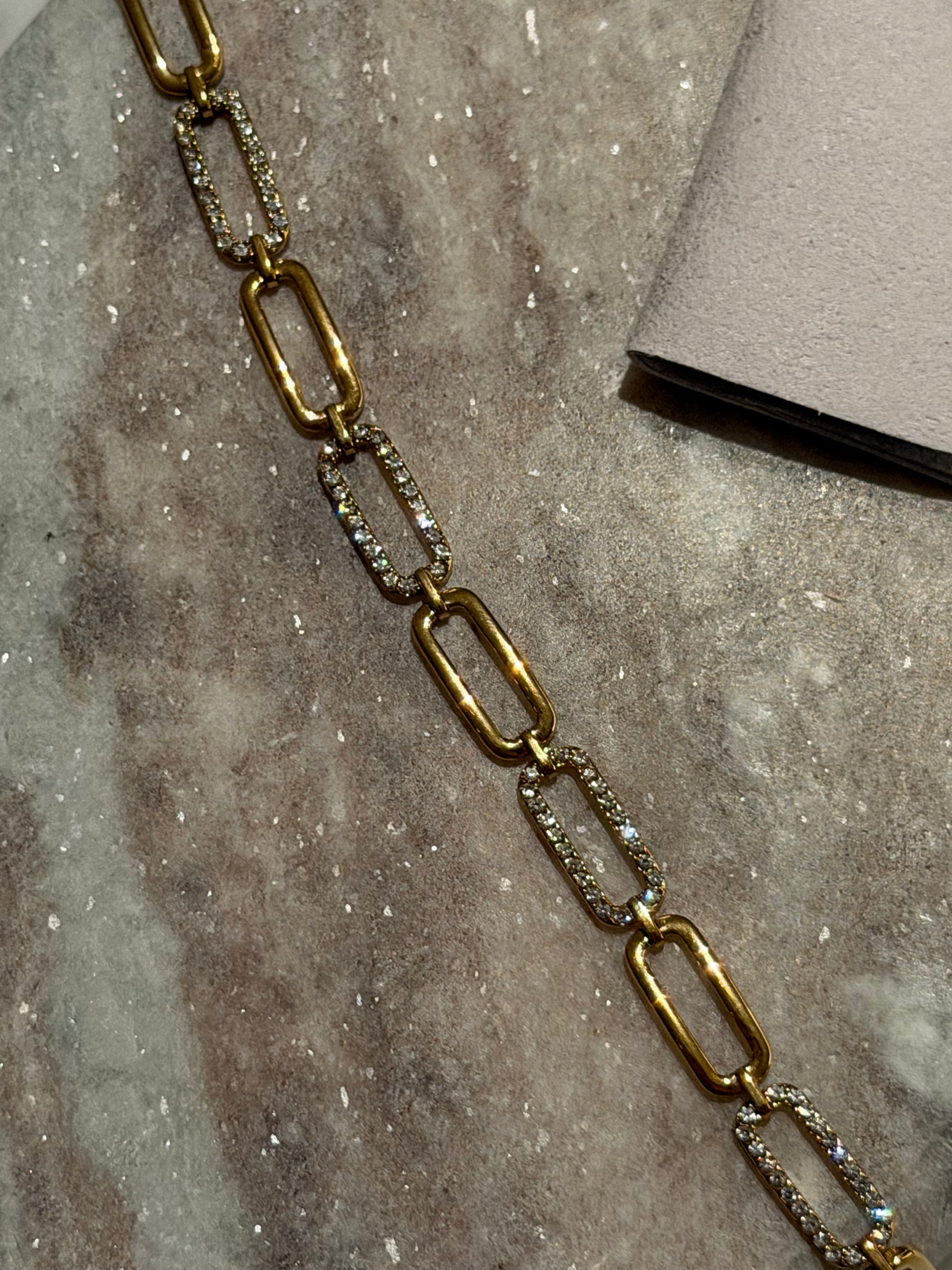 Gold chain bracelet on a textured stone surface
