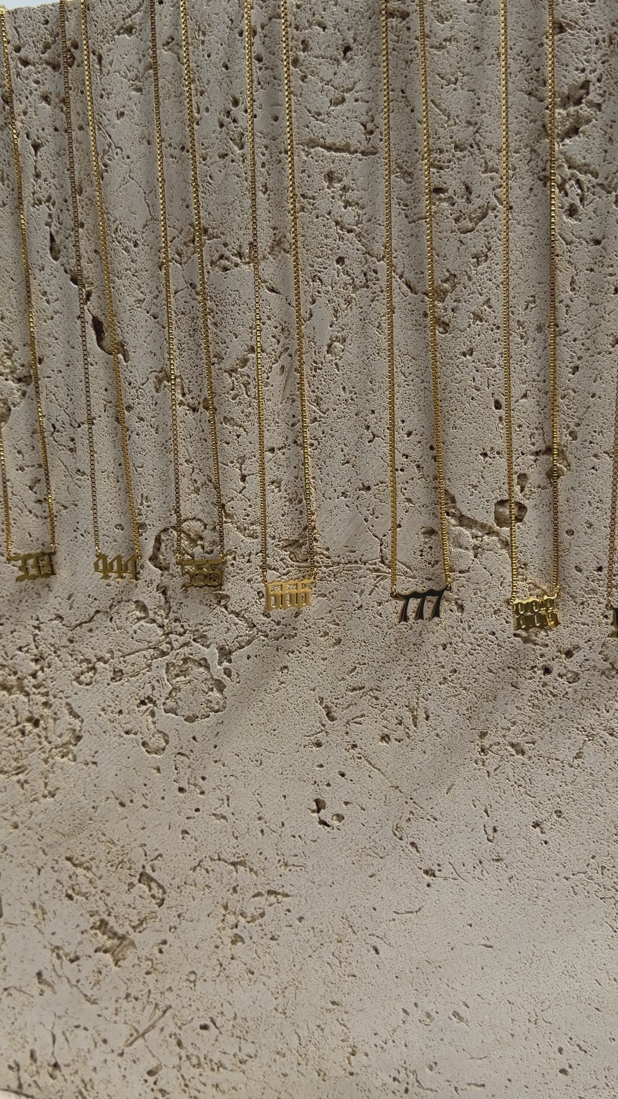 Gold angel number necklaces on travertine background
